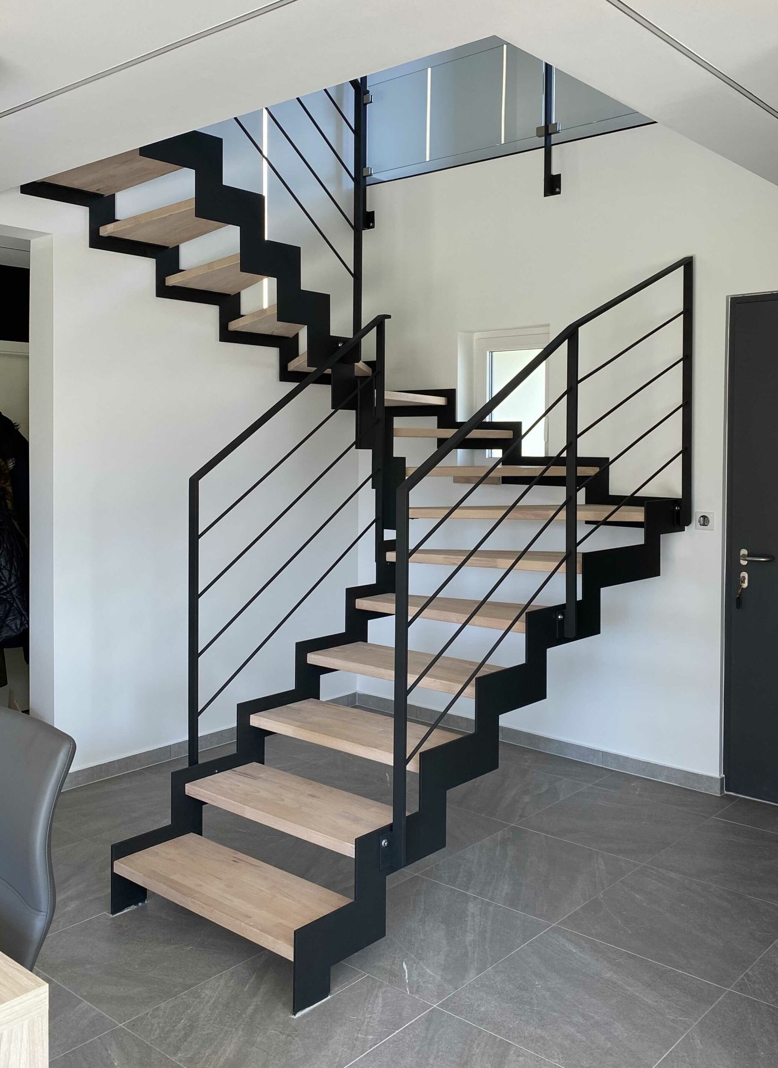 Escalier contemporain en métal noir avec des marches en bois clair dans un intérieur moderne.